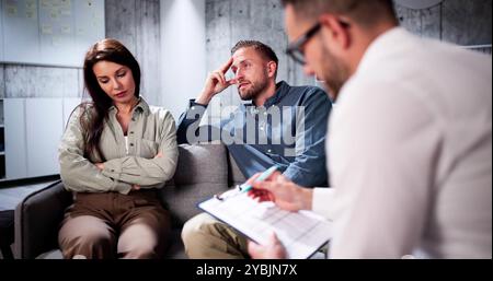 Sad Young Couple Sitting On Sofa With Female Psychologist Stock Photo