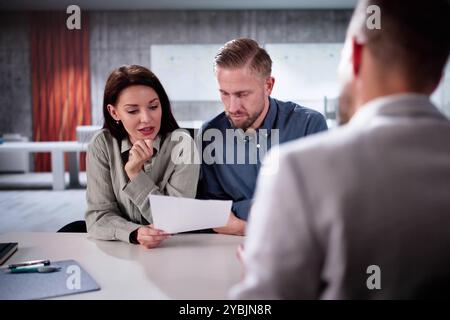 Financial Consultant Explaining New Project Investment To Young Couple In Office. Real Estate Agent Discussing Mortgage Options With Family. Mortgage Stock Photo