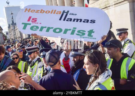 London, UK. 19th October 2024. An Israel supporter holds an anti-Hezbollah and anti-Hamas placard during a counter-protest. Thousands of pro-Palestine protesters gathered in Trafalgar Square calling for a ceasefire and for the UK government to stop arming Israel as Israel continues its attacks on Gaza. Credit: Vuk Valcic/Alamy Live News Stock Photo