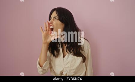 Young hispanic woman shouting against an isolated pink background looks determined and expressive Stock Photo