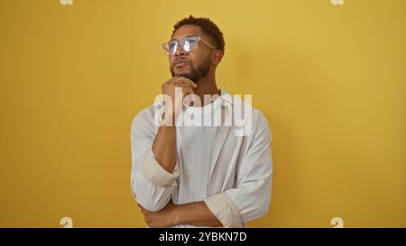 Handsome young african man wearing glasses thinking over isolated yellow background Stock Photo