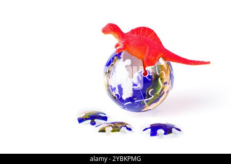 Bright red dinosaur standing in a globe made of puzzle pieces with scattered additional pieces, set against a clean white background, representing the Stock Photo