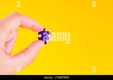 Close-up of a hand holding a single globe puzzle piece, emphasizing the importance of individual contribution in a larger context. Stock Photo