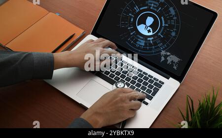 A person operates a laptop displaying a digital interface featuring a medical icon, symbolizing telemedicine. Stock Photo