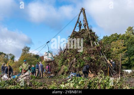 Villagers in Chiddingfold, Surrey, England, UK, building a giant bonfire on the village green during October 2024. This is in preparation for the annual bonfire night celebration event complete with traditional Guy Fawkes and fireworks display due to take place in early November. Stock Photo