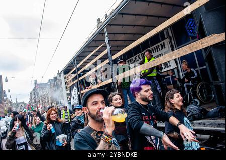 Amsterdam, Netherlands. 19th Oct, 2024. Participants are seen dancing and drinking during the parade. ADEV (Amsterdam Danst Ergens Voor), which means 'Amsterdam Dances For A Cause' organized for the 12th time, its an annual demonstration for squatting, free spaces, and affordable housing in the city Credit: SOPA Images Limited/Alamy Live News Stock Photo