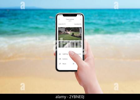 Monitoring home security cameras from the beach using a smartphone app, ensuring peace of mind while enjoying a seaside vacation and keeping an eye on Stock Photo