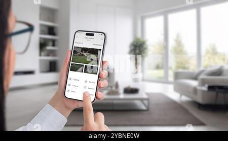 Smart home security. A woman monitors outdoor cameras with her smartphone, ensuring safety and control over her home environment from anywhere Stock Photo