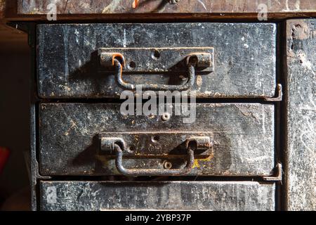 Old black metal industrial cabinet with rustic metal drawers in a workshop Stock Photo