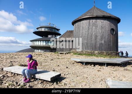 Young Woman on bench Chapel of Saint Lawrence building  on Snezka Mountain Sniezka Poland Europe Stock Photo