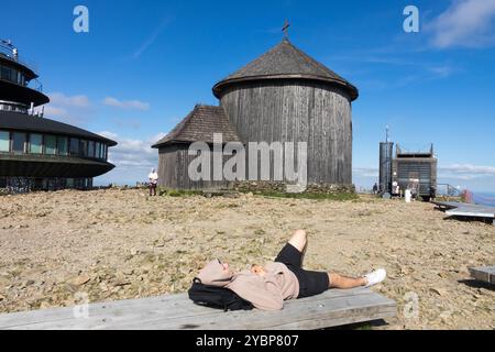 Young Man relaxing on bench Chapel of Saint Lawrence on Snezka Mountain Sniezka Poland Europe Stock Photo