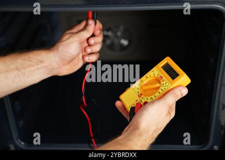 Repairman testing oven element with multimeter, closeup Stock Photo