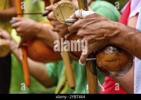Hands of a musician playing an Afro Brazilian percussion musical instrument called a berimbau during a capoeira performance in the streets of Brazil Stock Photo