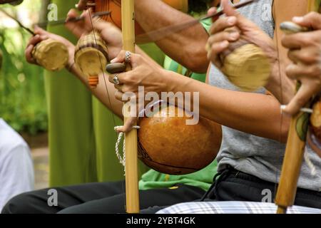 Several musicians playing an Afro Brazilian percussion musical instrument called the berimbau during a capoeira performance in the streets of Brazil Stock Photo