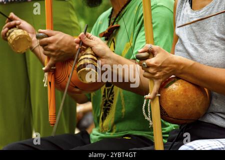 Musicians playing an Afro Brazilian percussion musical instrument called a berimbau during a capoeira performance in the streets of Brazil Stock Photo