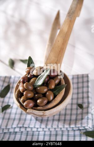 Presentation of a small group of black olives on wooden ladle Stock Photo