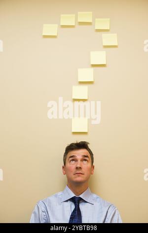 Caucasian middle aged businessman under sticky note notes in the shape of a question mark Stock Photo