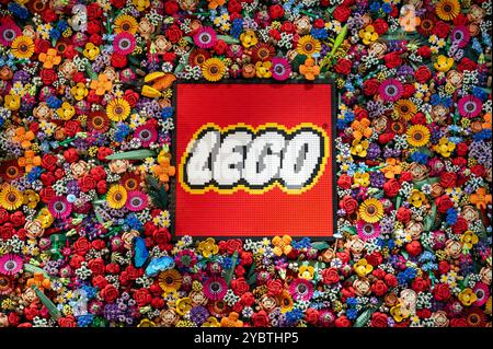 The lego logo made with plastic bricks, surrounded by colorful flowers also made with bricks Stock Photo