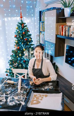 Young smiling woman kneading gingerbread cookie dough on the table Stock Photo