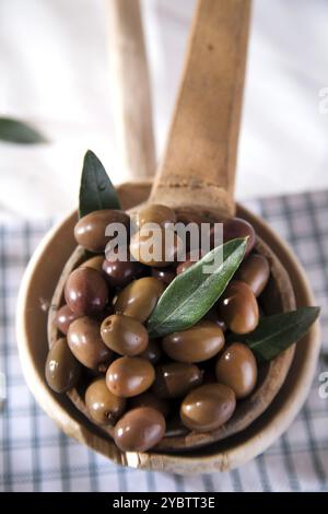 Presentation of a small group of black olives on wooden ladle Stock Photo