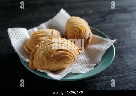 A plate of Malaysian deep fried curry puff or epok-epok isolated on dark background. Also known as Karipap Pusing. Stock Photo