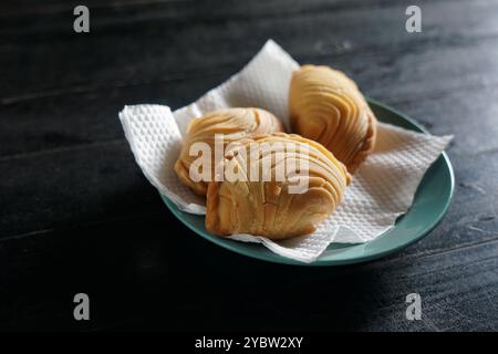 A plate of Malaysian deep fried curry puff or epok-epok isolated on dark background. Also known as Karipap Pusing. Stock Photo