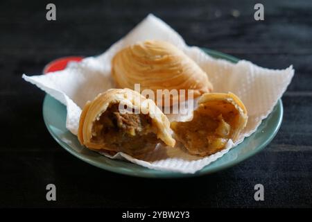 A plate of Malaysian deep fried curry puff or epok-epok isolated on dark background. Also known as Karipap Pusing. Stock Photo