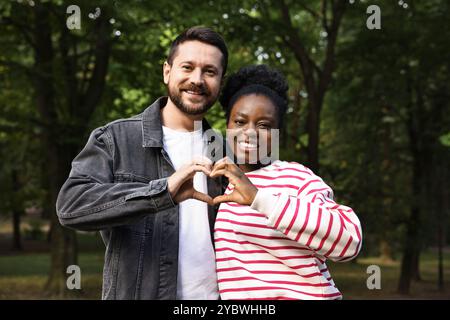 International relationships. Lovely couple making heart with hands outdoors Stock Photo