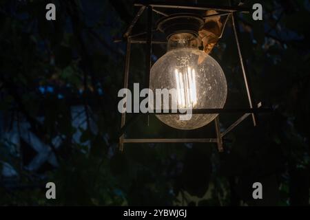 Glow in the Dusk: Big Round Light Bulb Illuminating the Night, Yard Garden Decoration Stock Photo