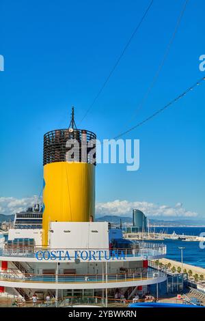 Barcelona. Espain -October 20,2024: Photograph of the yellow funnel of Costa Fortuna cruise ship docked at Barcelona port, with the city's skyline in Stock Photo