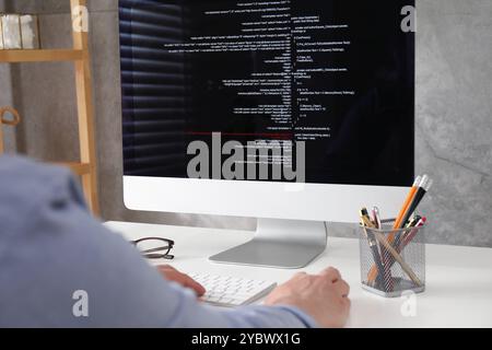 Programmer working with computer at white desk in office, closeup Stock Photo