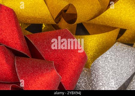 This image displays a close-up of several glittery ribbons in gold, red, and silver. Stock Photo