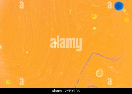 This image displays an abstract pattern with a predominantly yellow background. Swirls and dots of various colors, including blue, orange, and green Stock Photo