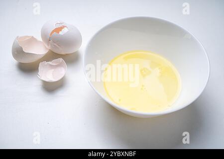 Raw egg white in a white bowl on the table and eggshells. High quality photo Stock Photo