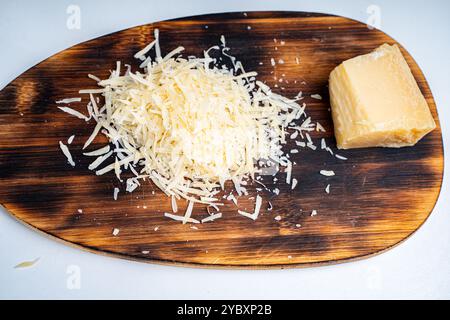 Grated Parmesan cheese and a piece on a wooden cutting board. High quality photo Stock Photo