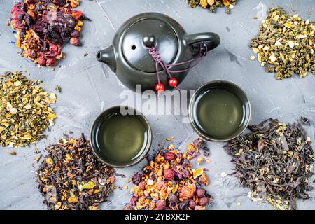 Various herbal dry teas, a teapot and cups on a gray table. View from above. High quality photo Stock Photo