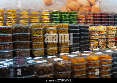Plastic containers with different dried fruits and nuts are neatly arranged on a supermarket shelf, creating an appetizing display for customers Stock Photo