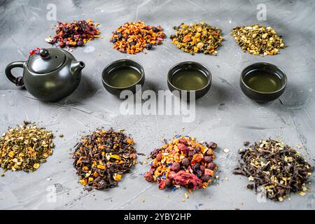 Dry tea of different varieties and a teapot with cups on a gray background. Tea ceremony, Tea with various additives, blending. High quality photo Stock Photo