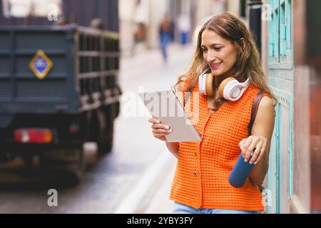 Latin woman holding reusable water bottle while using digital tablet Stock Photo