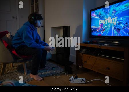 11 year old boy wearing headphones whilst gaming at home whilst playing Fortnight on his Nintendo Switch console, London, England, United Kingdom Stock Photo