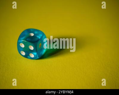 Blue dice on yellow paper background. Cardboard bright background with texture. Concept of luck, testing fate, lottery, decision making. Place for tex Stock Photo