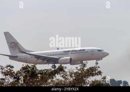 A small Air Peace aircraft flying low over trees as it descends into the airport for landing, showcasing the approach of a commercial flight Stock Photo