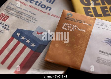 Fullerton, California, USA - October 20, 2024: Afternoon light shines on table of election materials and a vote by mail ballot. Stock Photo