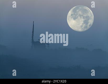 The October 'Hunters' Moon setting on a misty morning over the relic of Brograve drainage mill, Norfolk Stock Photo