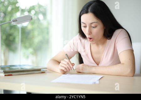 Amazed asian woman signing contract in a desk at home Stock Photo