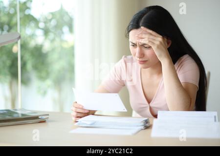 Worried asian woman complaining checking invoice sitting at home Stock Photo