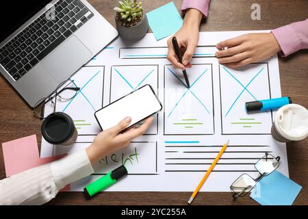 Developing UI design. Designers creating website wireframe on paper at wooden table, top view Stock Photo