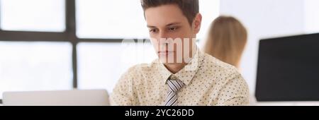 Manager with serious facial expression works on laptop Stock Photo