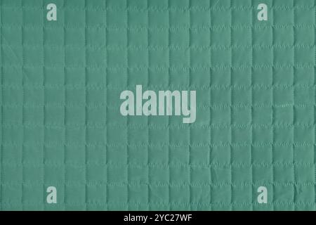 Checkered stitching pattern, green quilted fabric background. Blanket or puffer jacket, stitch square texture close up, macro. Wallpaper, backdrop. Stock Photo