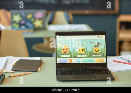 Background image of open laptop in kids classroom with cute characters on screen no people Stock Photo